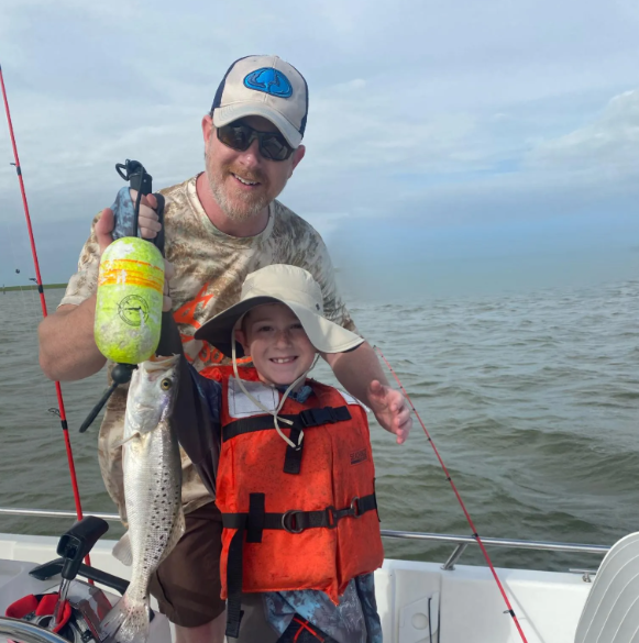 A man and child on a boat holding a fish