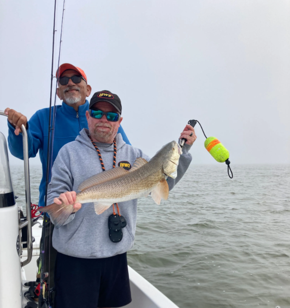 Two men on a boat holding a large fish