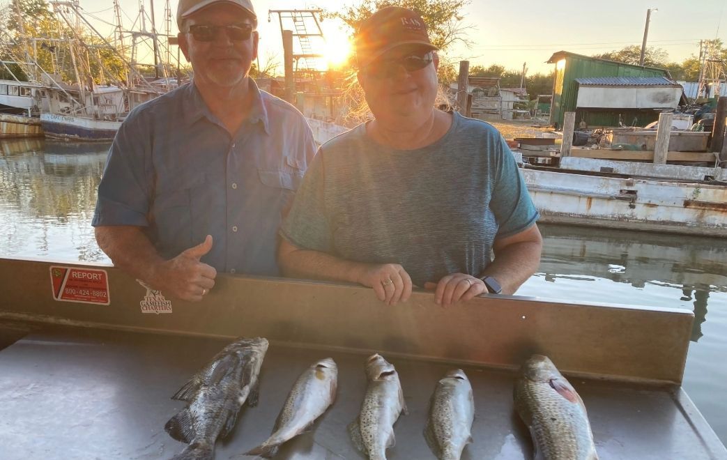 Two men are standing next to a table with fish on it.