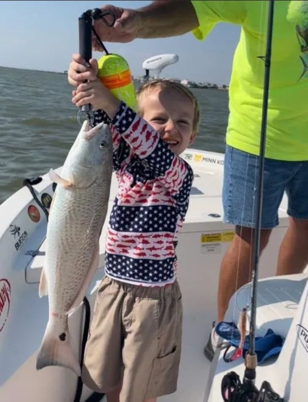 A little boy is holding a fish on a boat