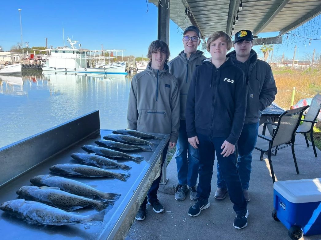 A group of young men standing next to a table full of fish.