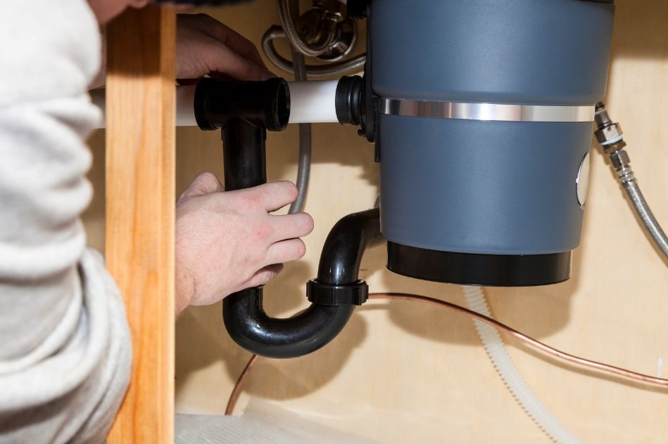 A plumber is fixing a sink with a wrench.