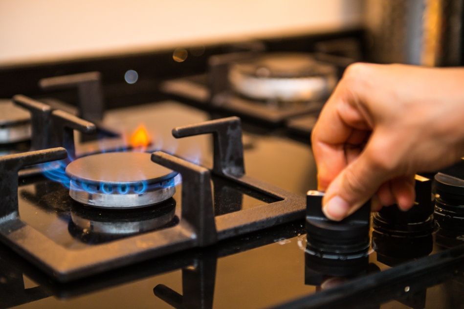 A person is turning a knob on a gas stove.