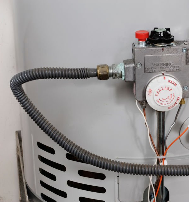 Close-up of a gas water heater with a flexible gas line connected to the control valve.