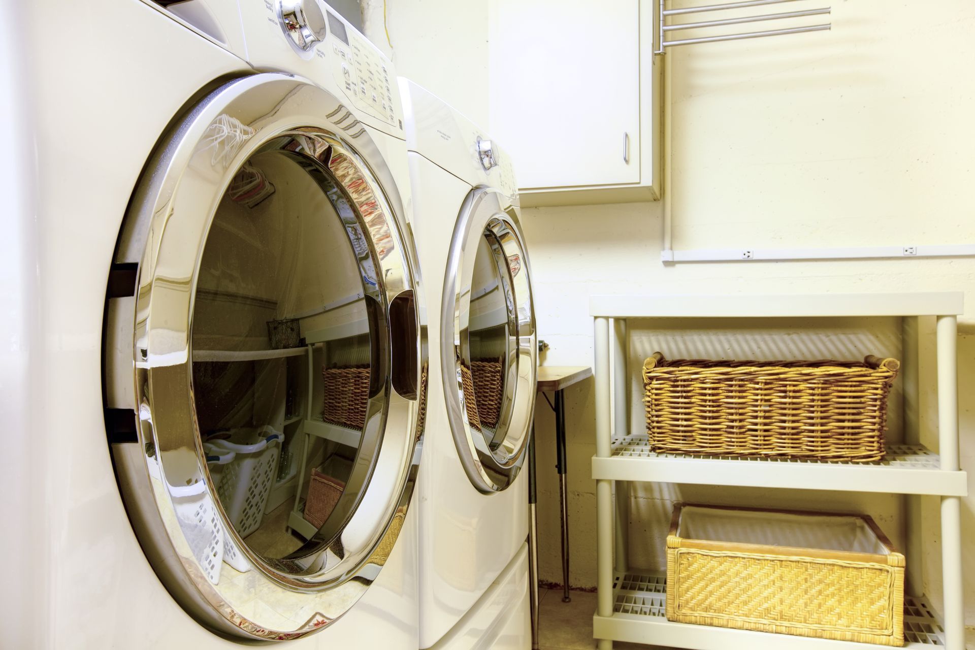 A laundry room with a washer and dryer and wicker baskets.
