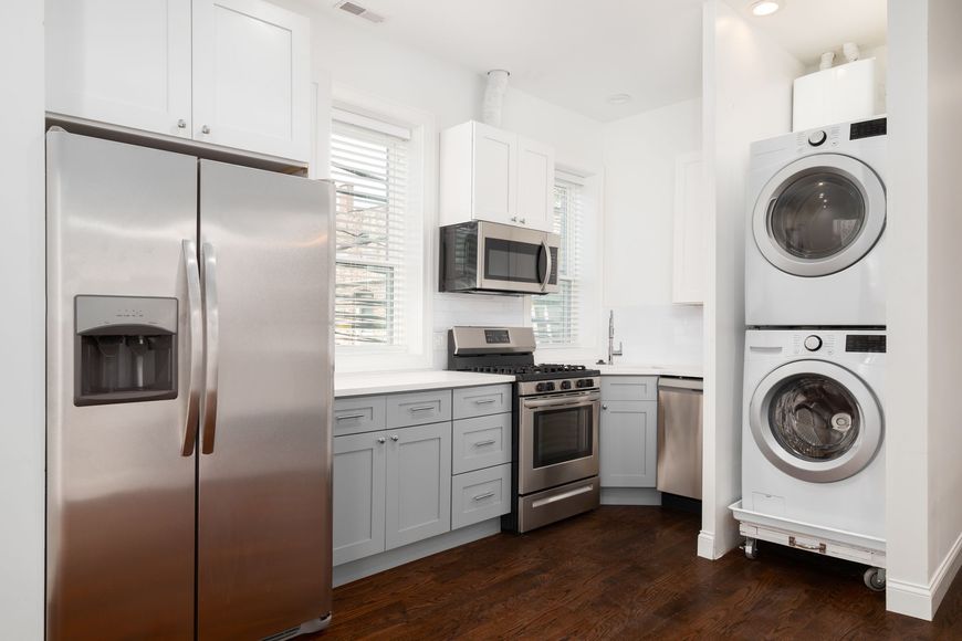 A kitchen with a refrigerator , washer and dryer stacked on top of each other.