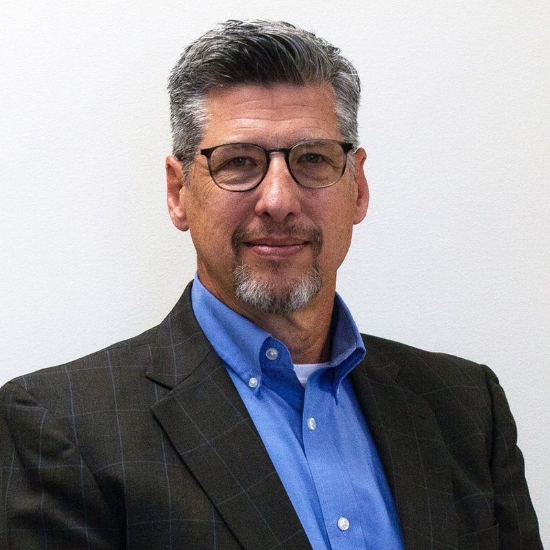 A bald man in a suit and tie smiles for the camera