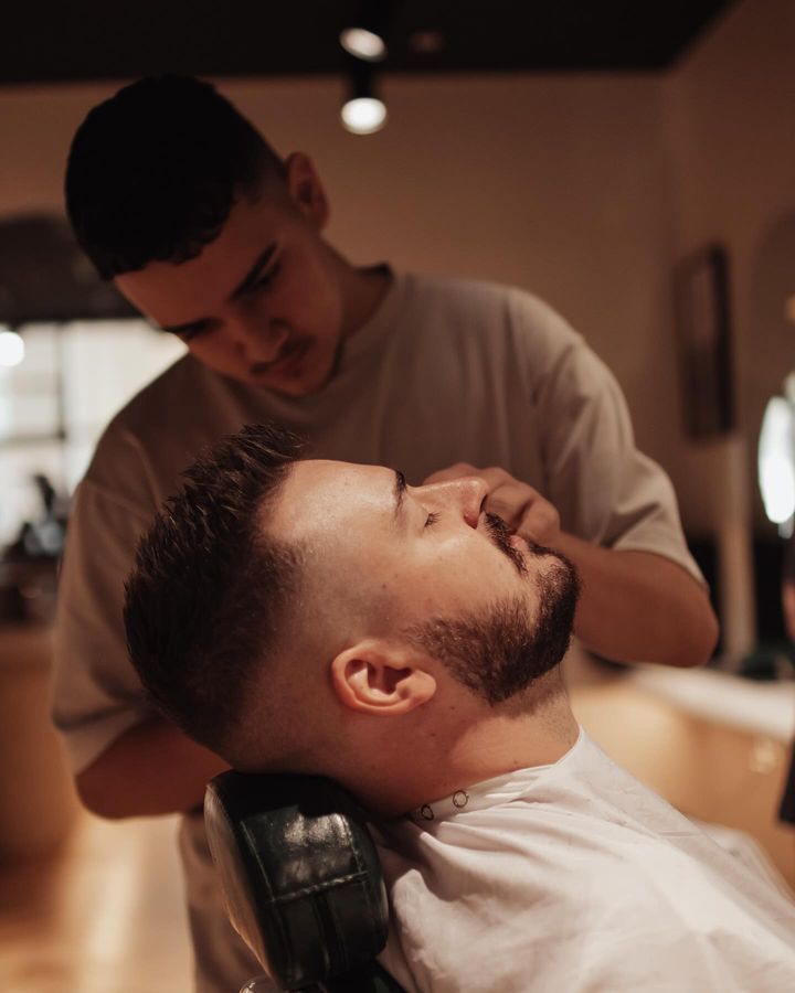 A Man With a Beard is Getting His Hair Cut by a Barber — Barber Bros & Co - Southport in Southport, QLD