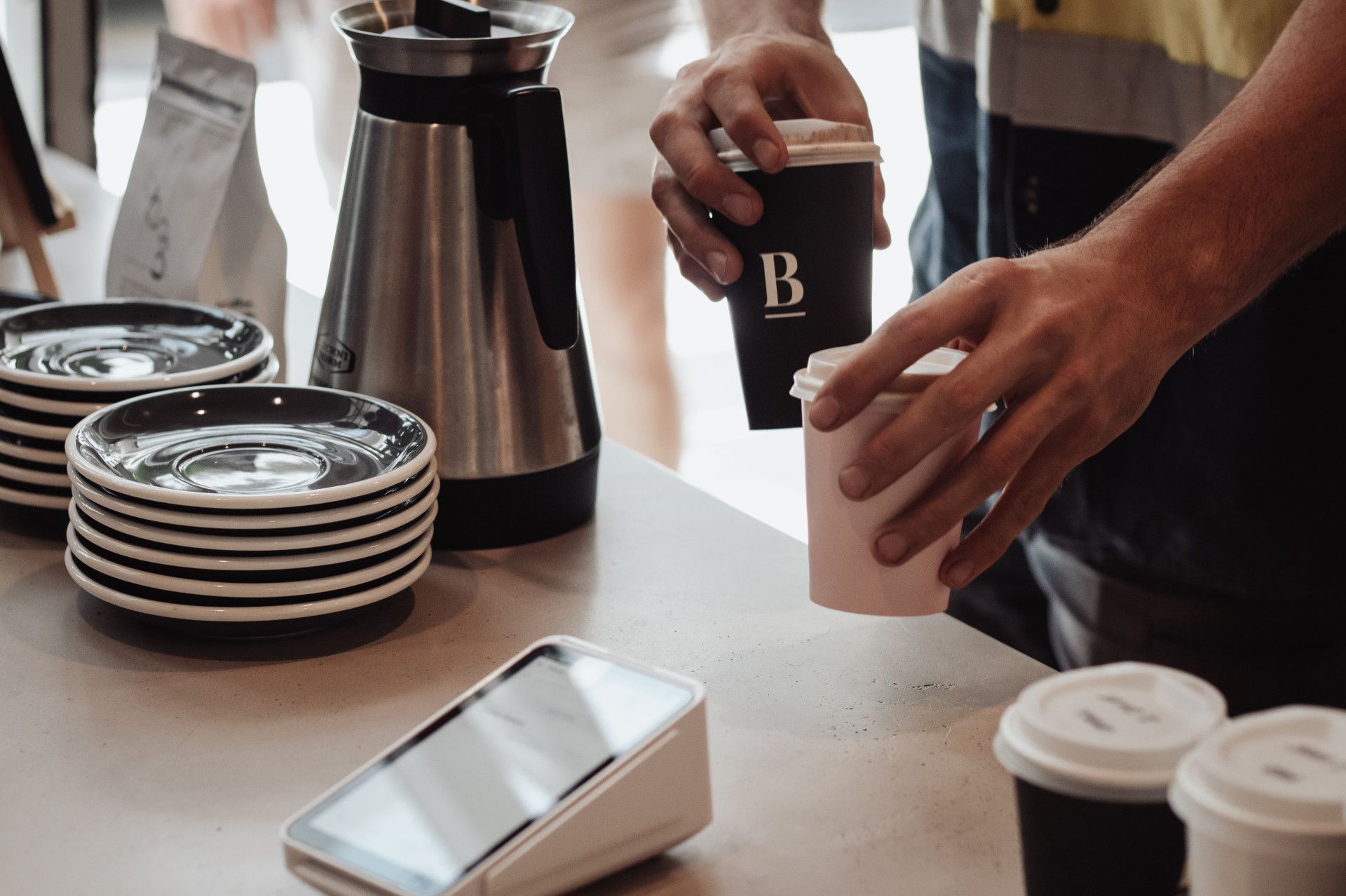 Man Passing Two Coffees Over Counter — Barber Bros & Co - Southport in Southport, QLD