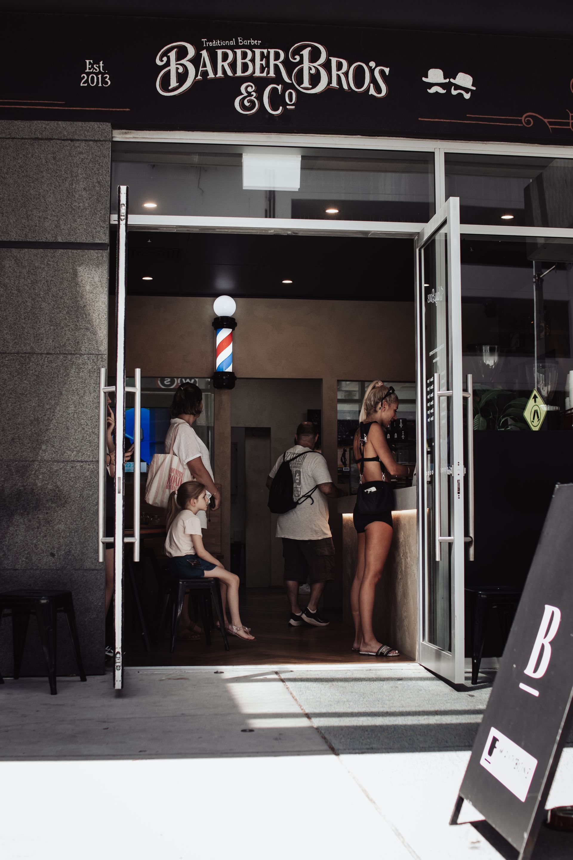 A Group of People Are Sitting at Tables Outside of a Espresso Bar — Barber Bros & Co - Southport in Southport, QLD