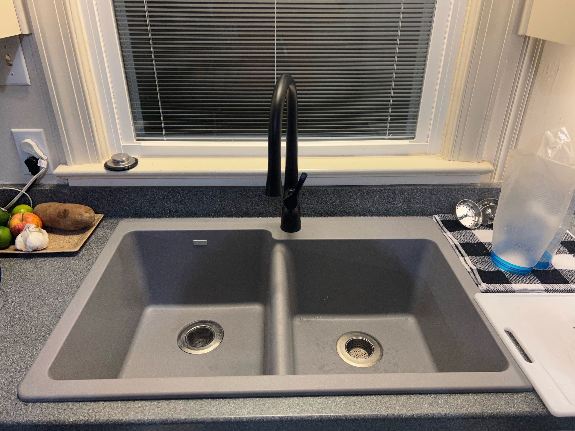A kitchen sink is sitting on a counter next to a window.