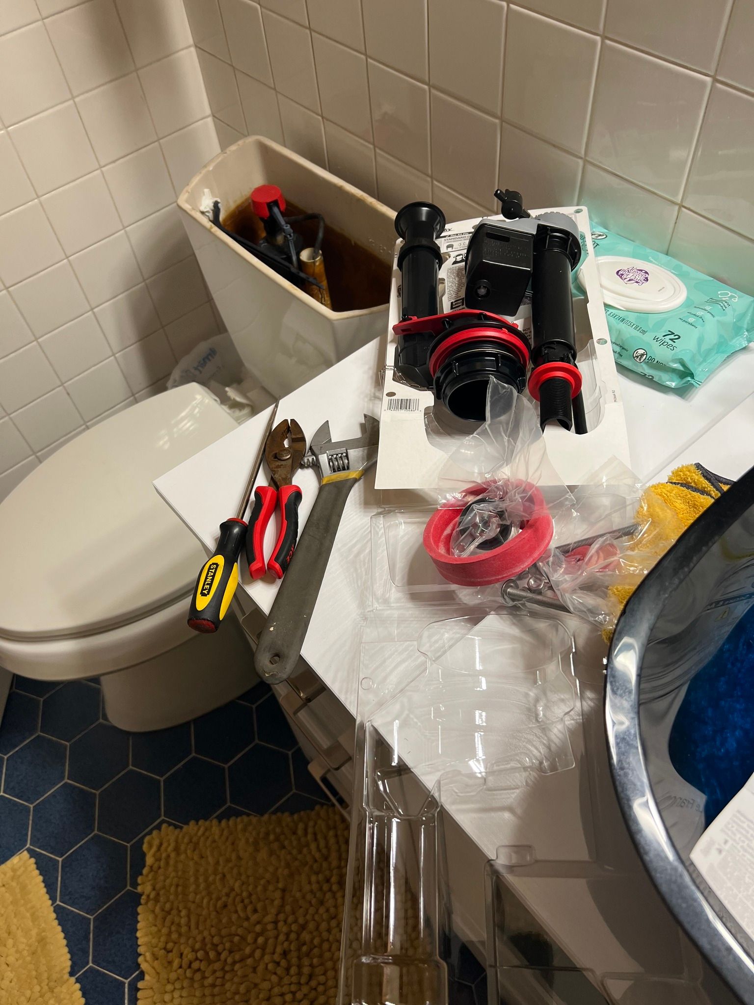 A bathroom with a toilet , sink , and tools on the counter.