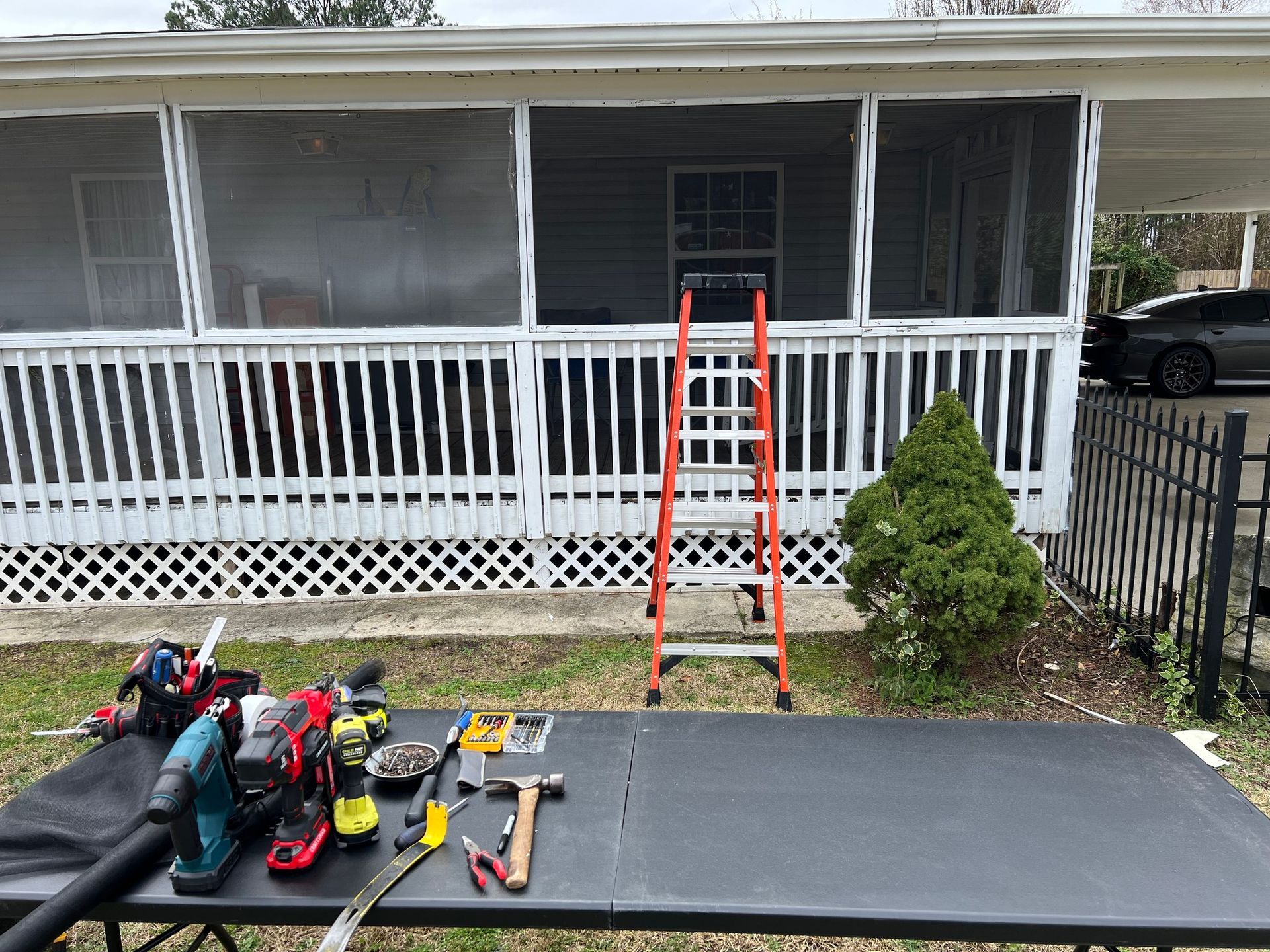 A table with tools and a ladder on it in front of a mobile home.