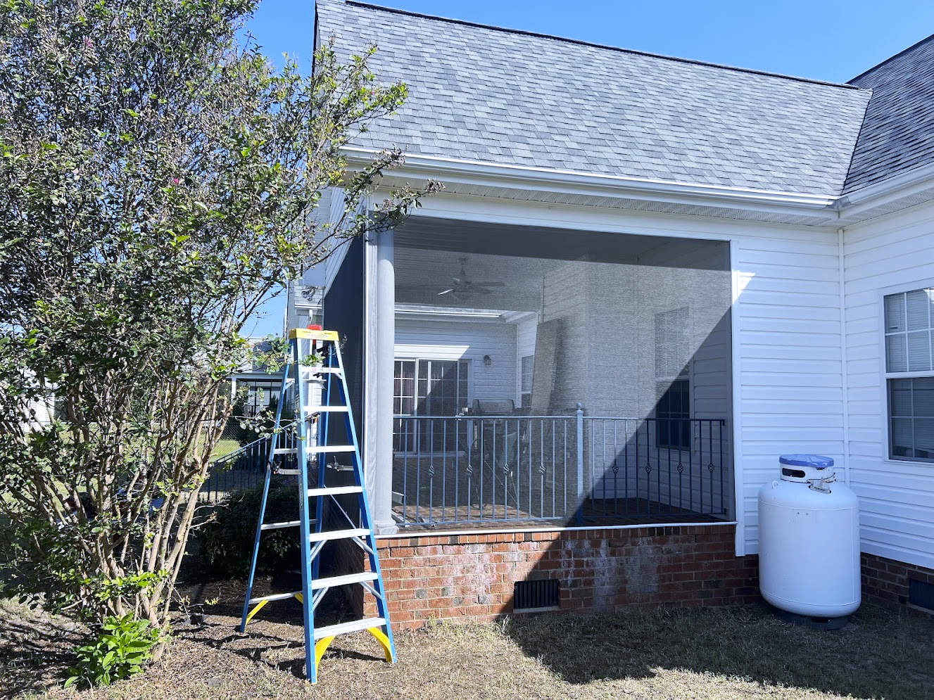 A screened in porch with a broken screen door and stairs leading up to it.