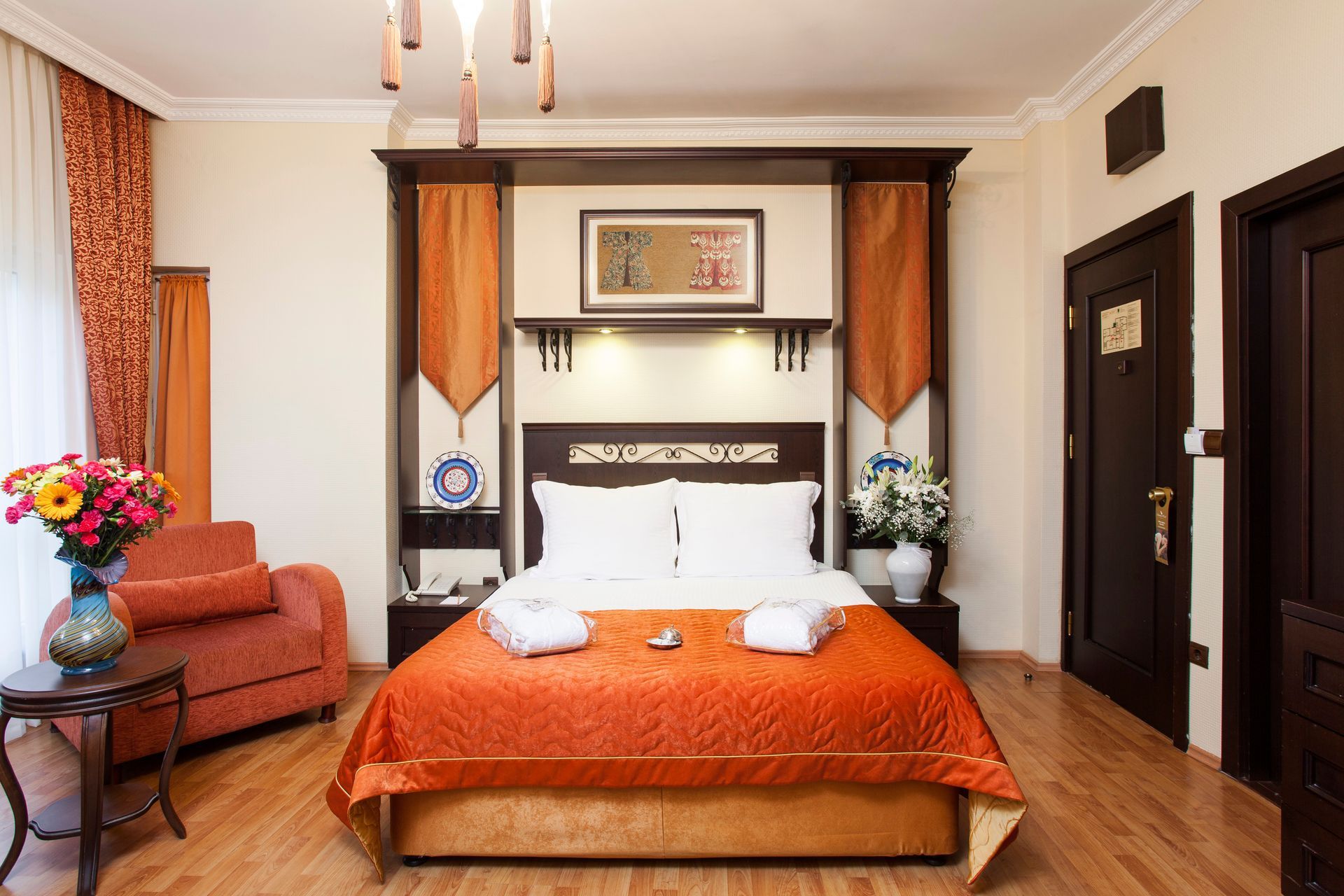 Hotel bedroom with an orange bedspread, wood furniture, and small seating area.
