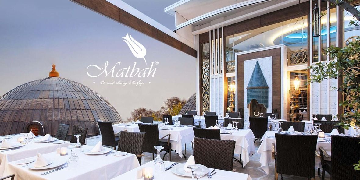 Outdoor restaurant with tables set for dining, overlooking a domed structure and city views.