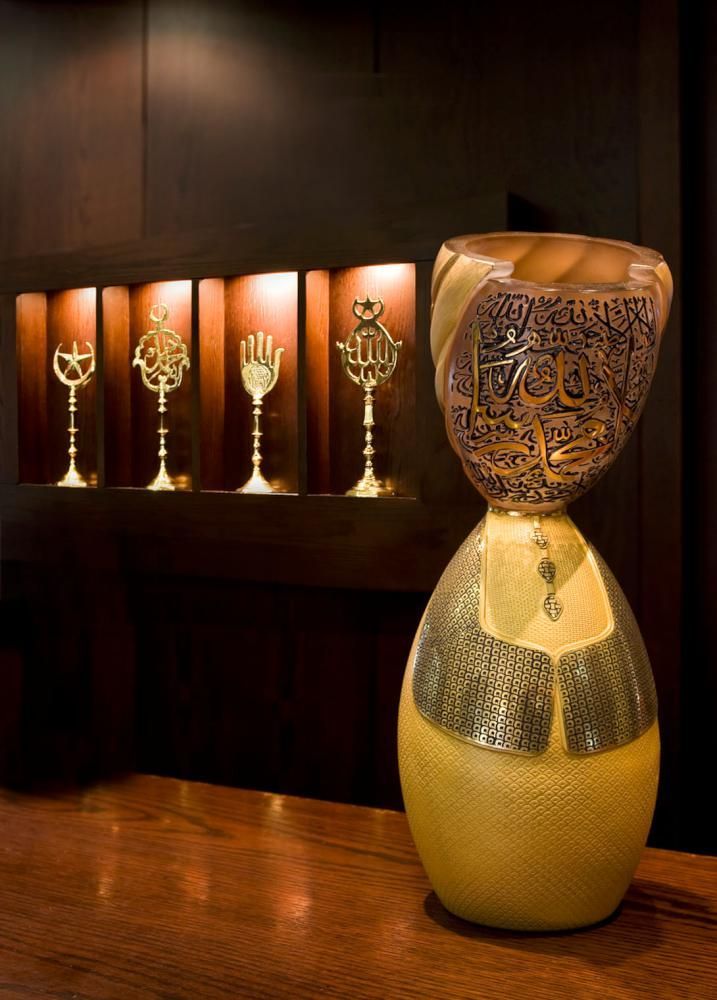 Hourglass sculpture and metallic religious symbols on a shelf.