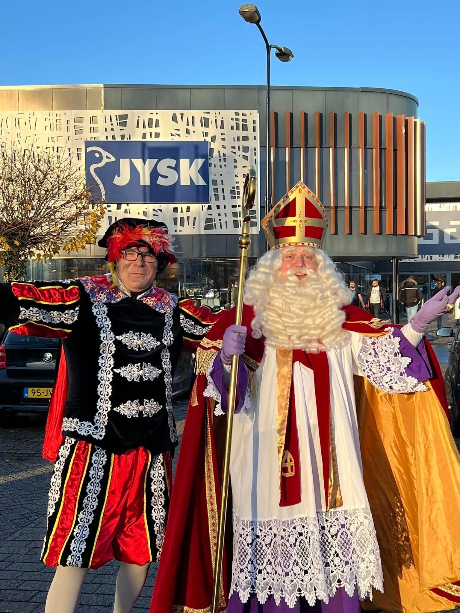 Twee mannen in kostuums staan ​​voor een JYSK-winkel
