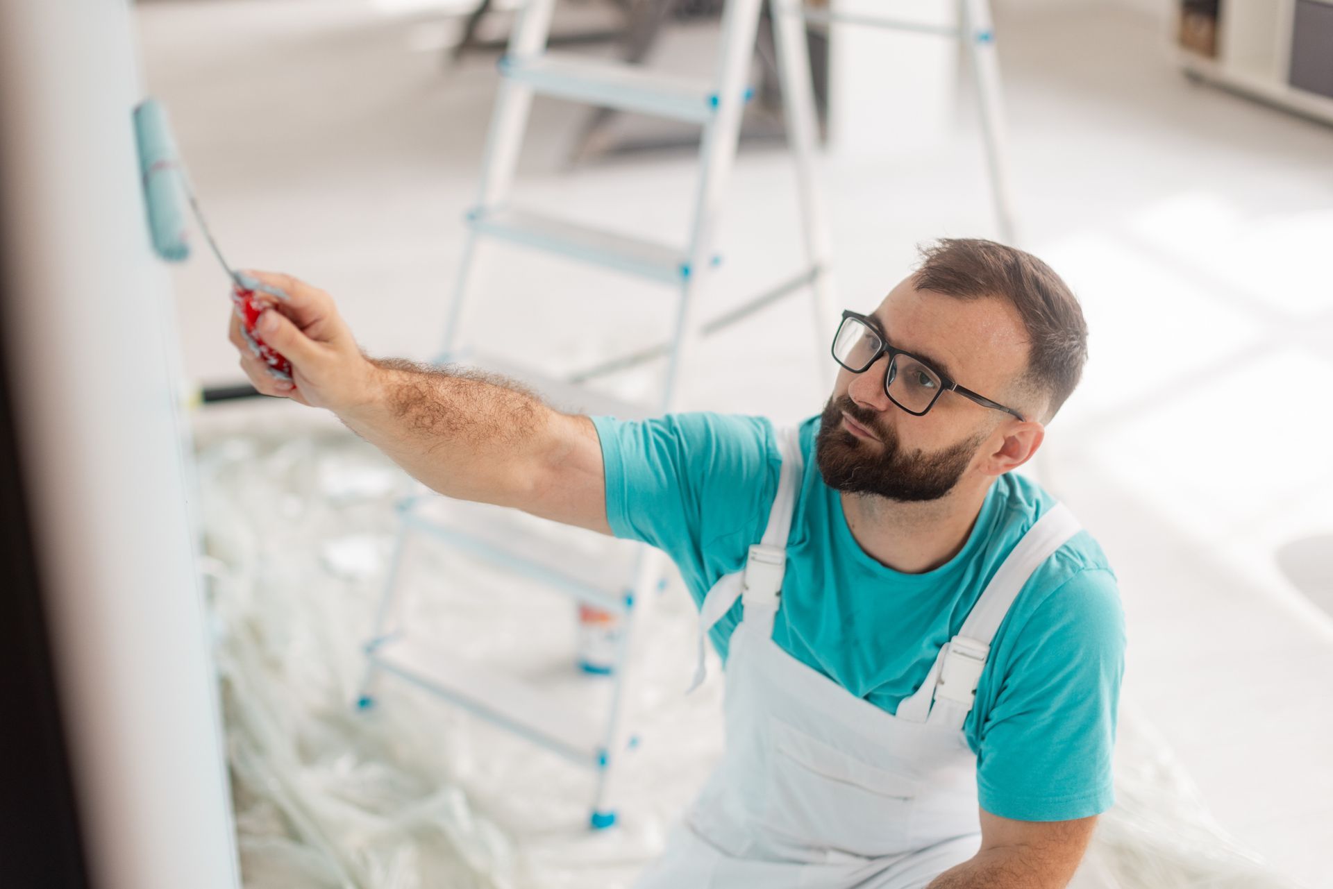 Residential painters applying light blue paint to indoor column in bright, modern living space. Residential painters applying light blue paint to indoor column in bright, modern living space.