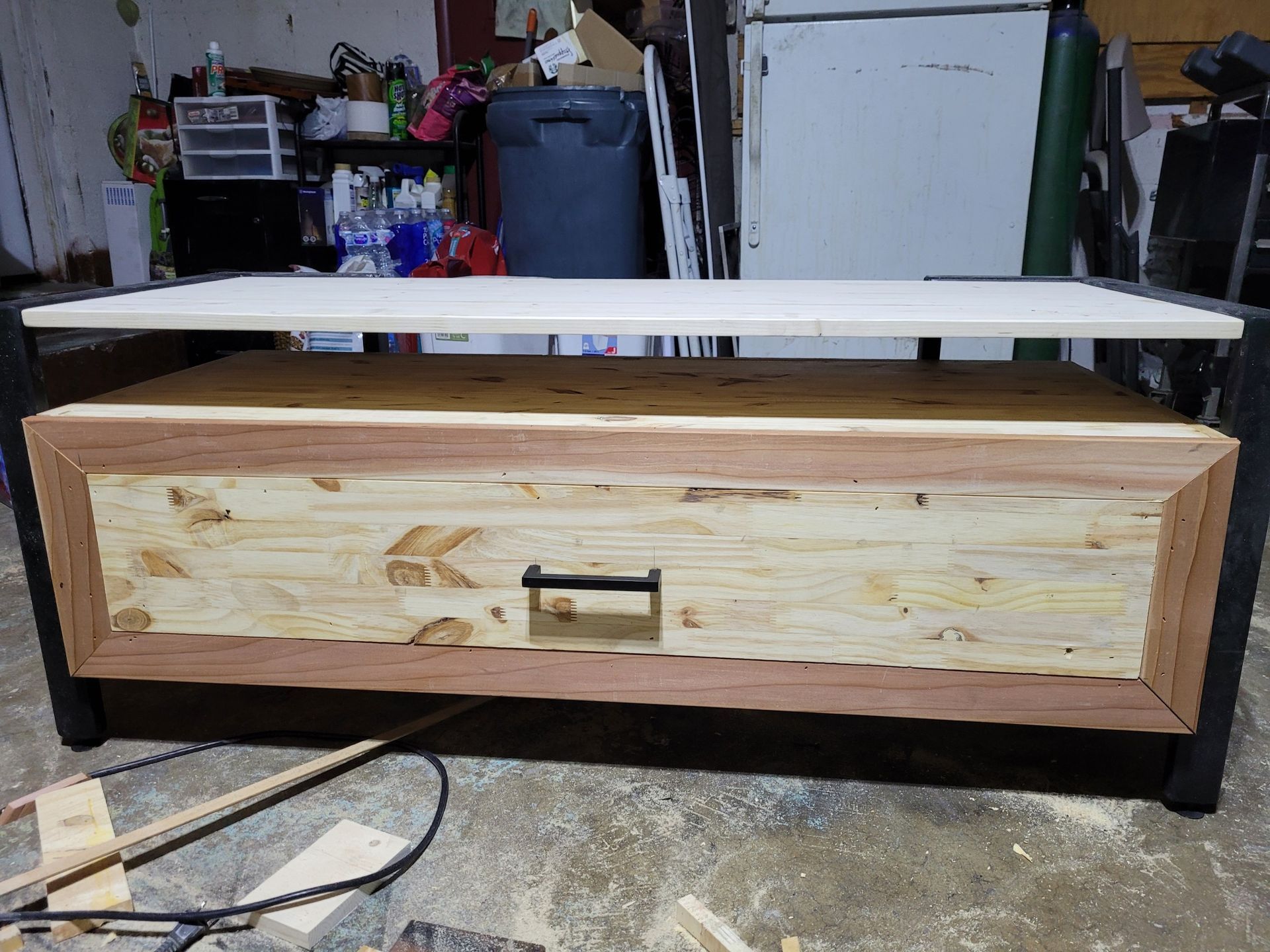Wooden, handmade cabinet with a drawer, on a concrete floor in a workshop.