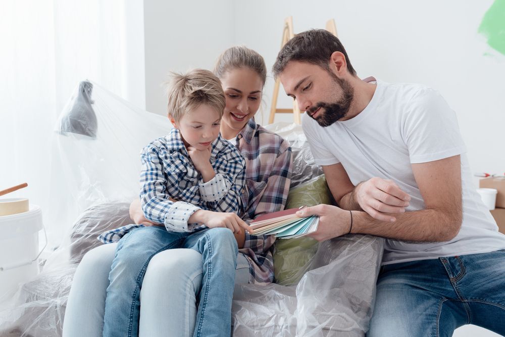 A family is sitting on a couch looking at paint samples.