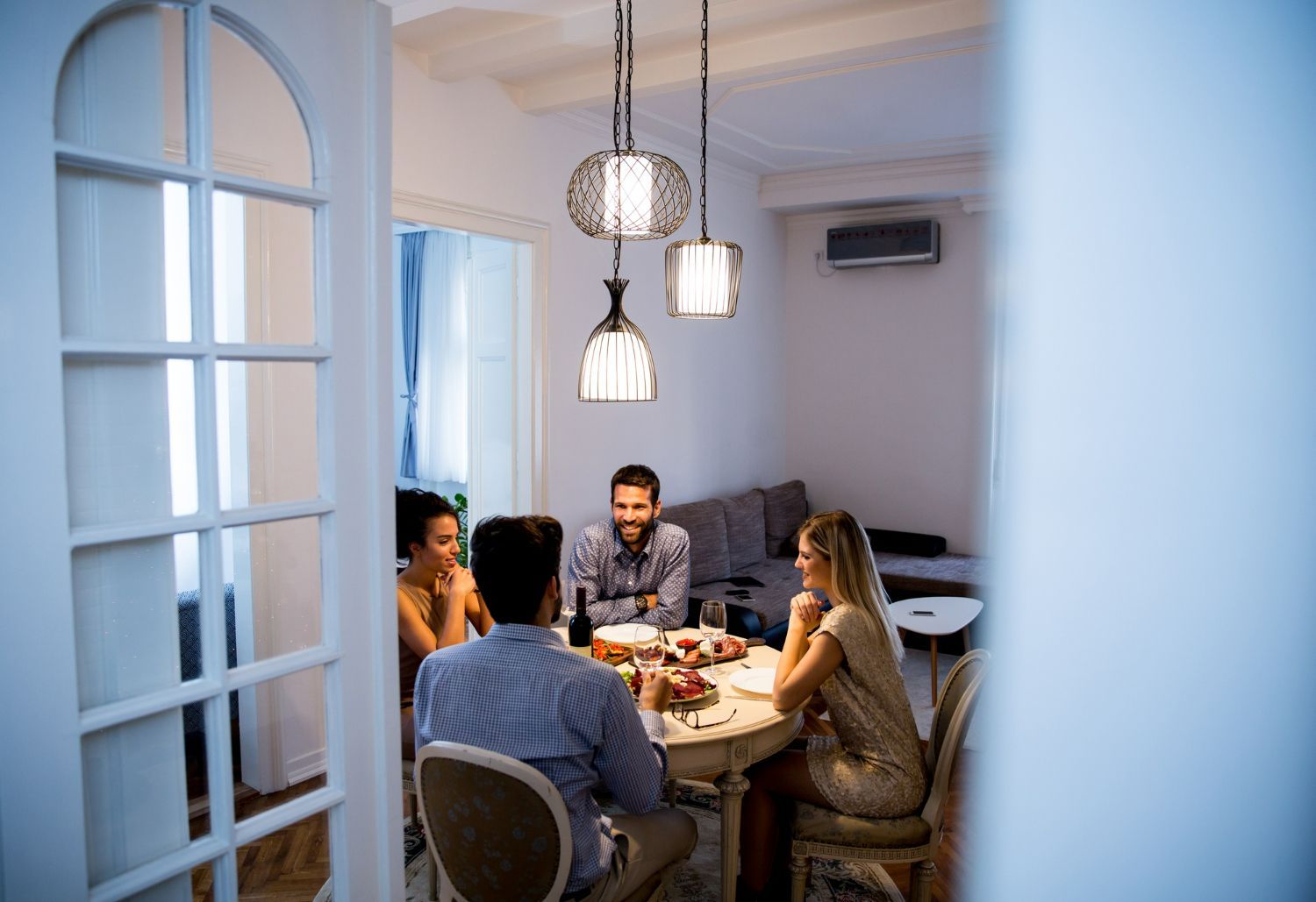 A group of people are sitting around a table in a living room.