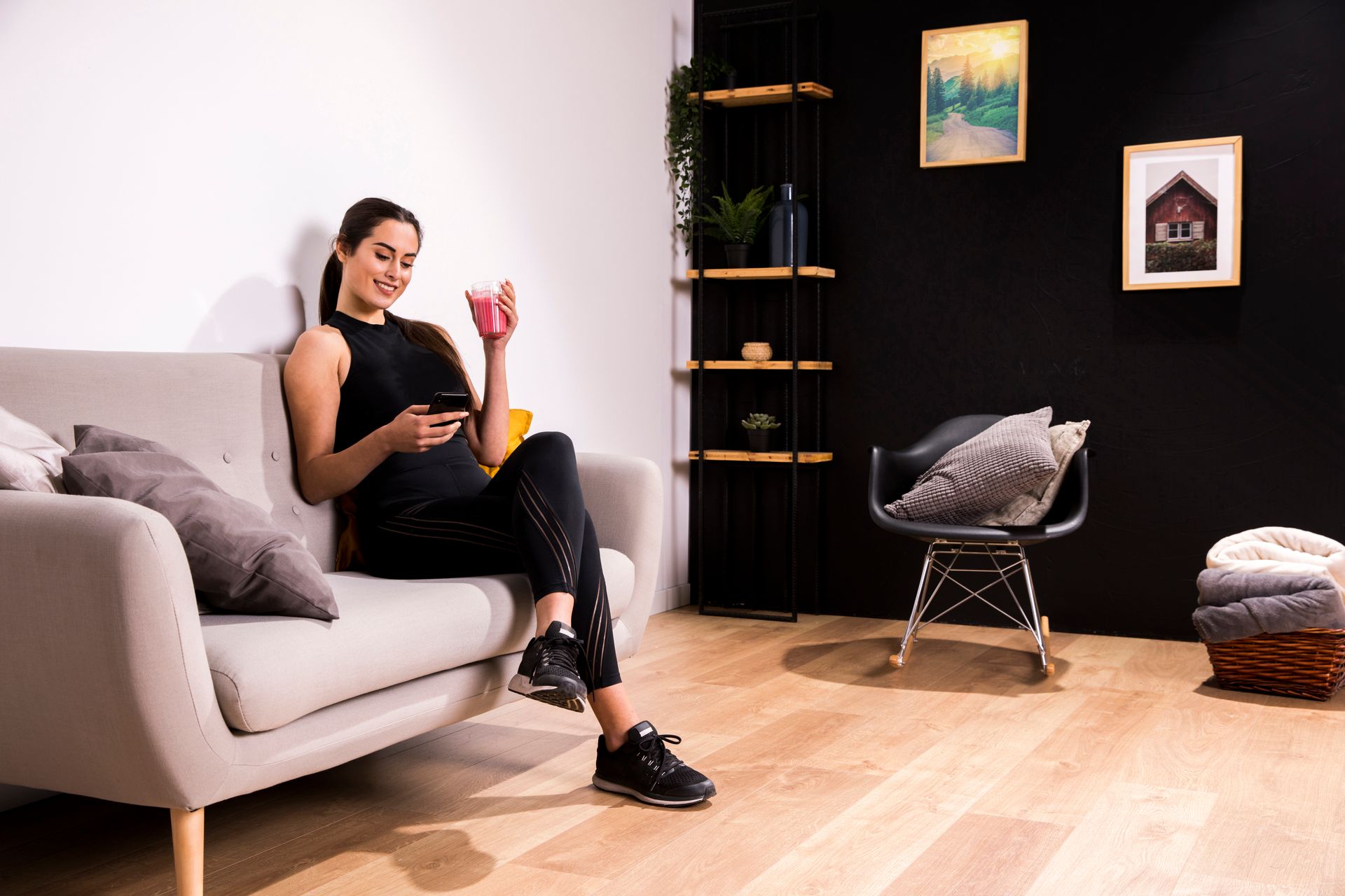 A woman is sitting on a couch in a living room holding a cup of coffee.