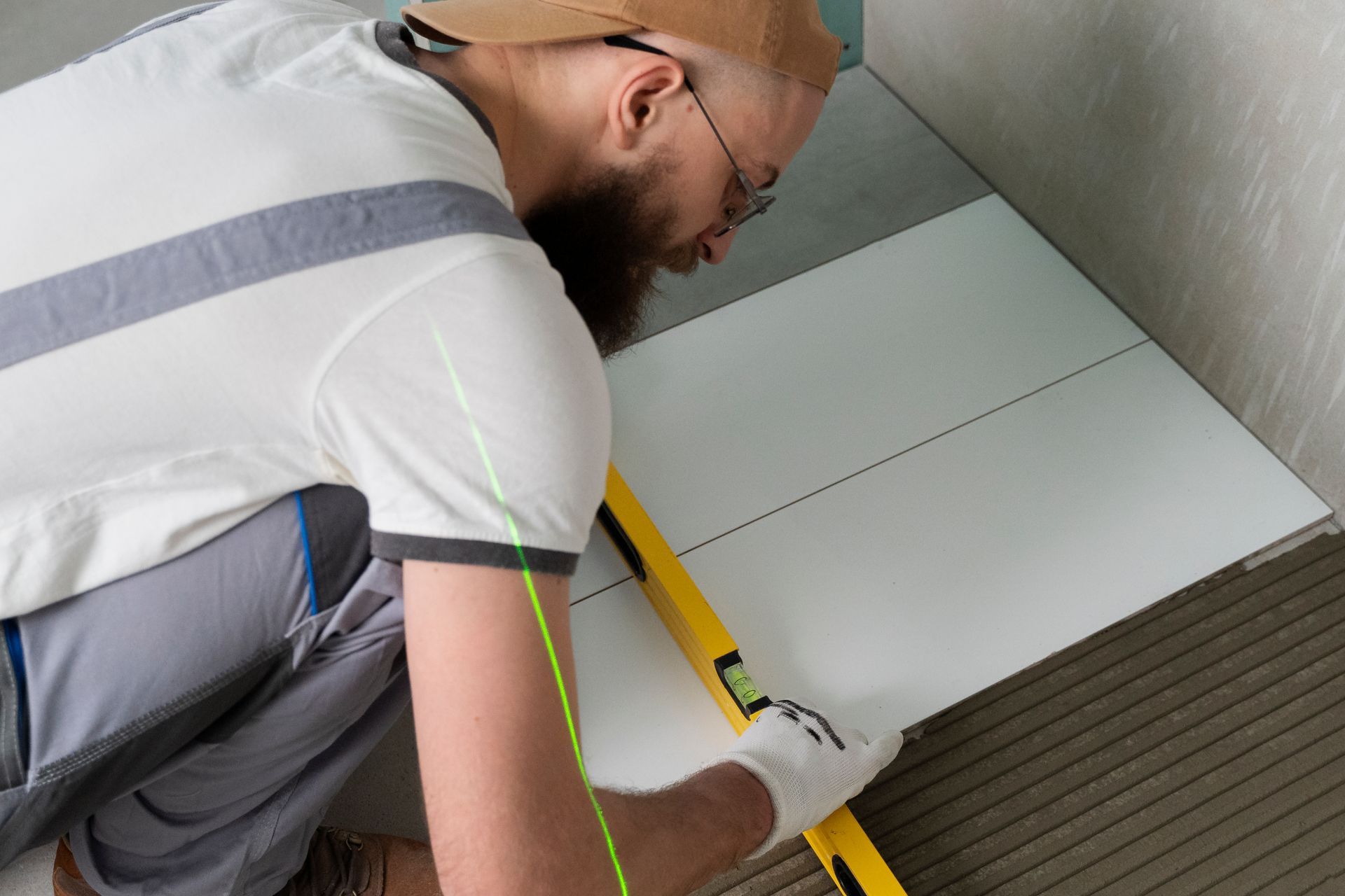 A man is measuring a tile floor with a level.