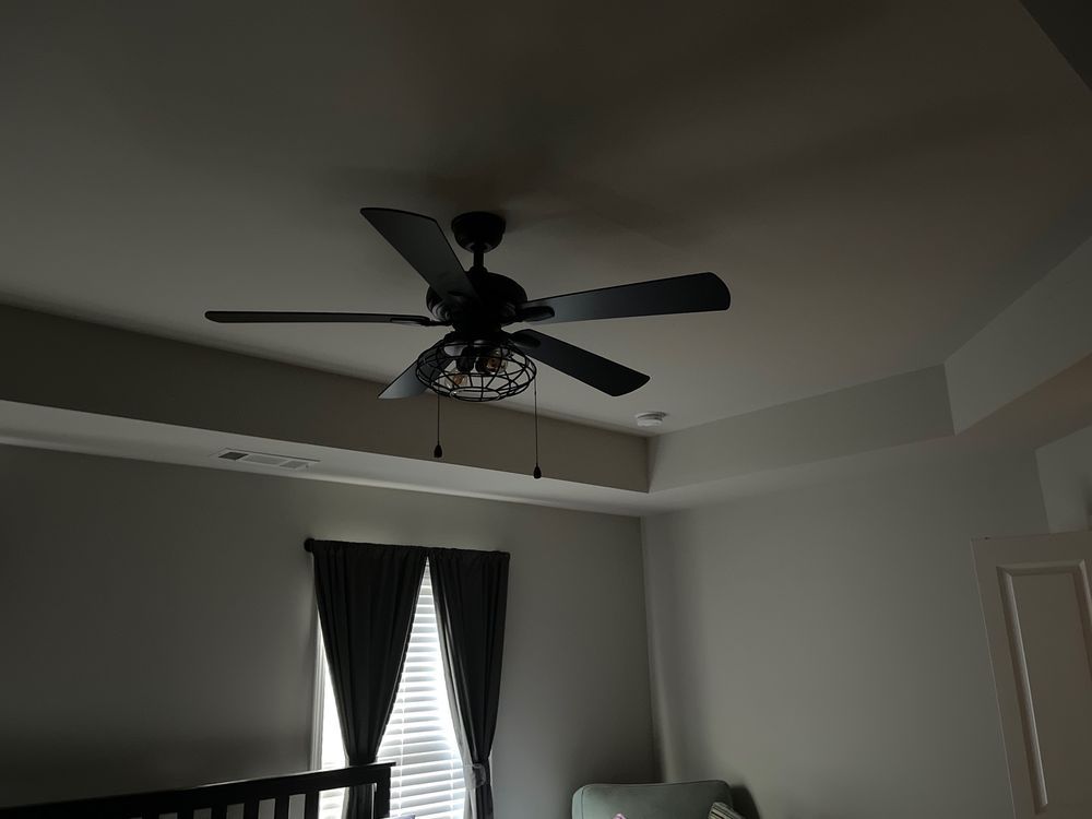 A bedroom with a ceiling fan hanging from the ceiling