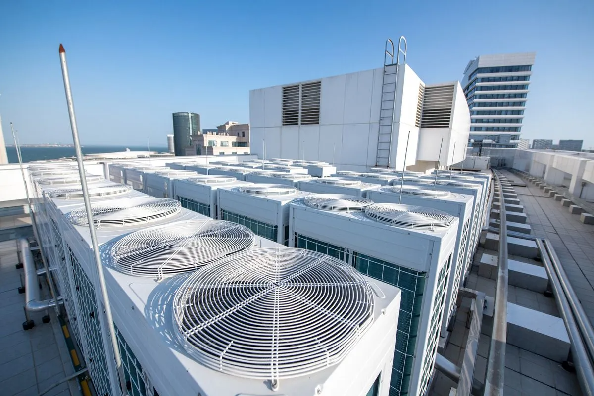 There are a lot of air conditioners on the roof of a building.