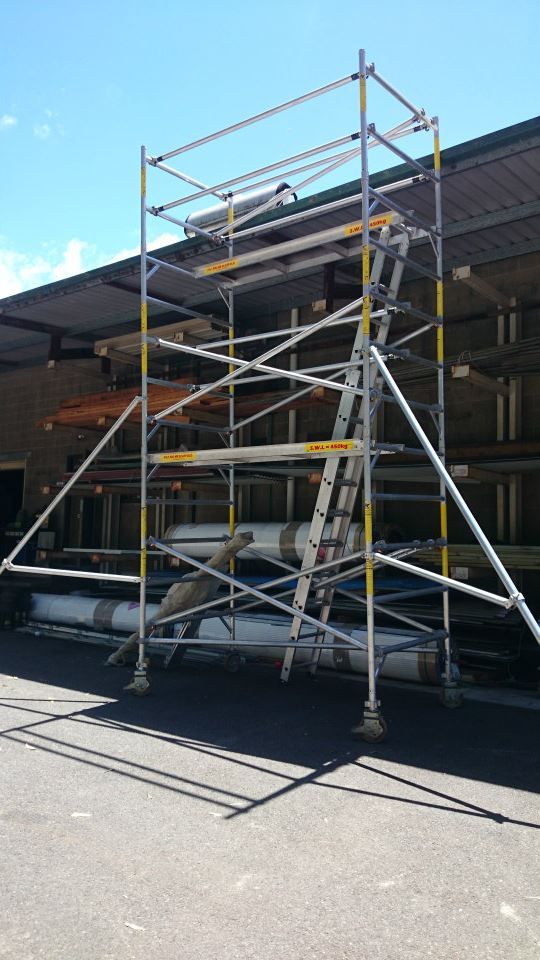 A Scaffolding With A Ladder Attached To It Is Sitting In Front Of A Building — Red Shed Hire In Wauchope, NSW