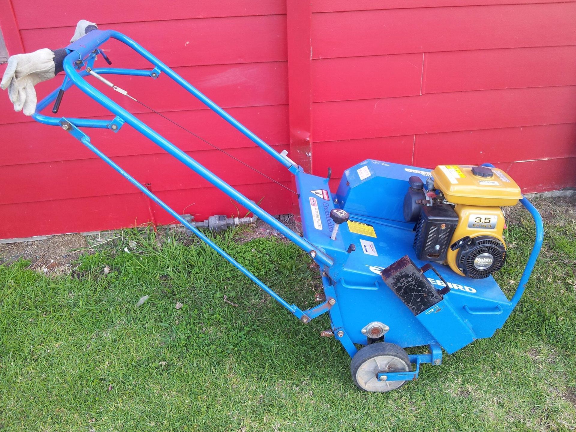 A Blue Lawn Mower Is Parked In Front Of A Red Fence — Red Shed Hire In Wauchope, NSW