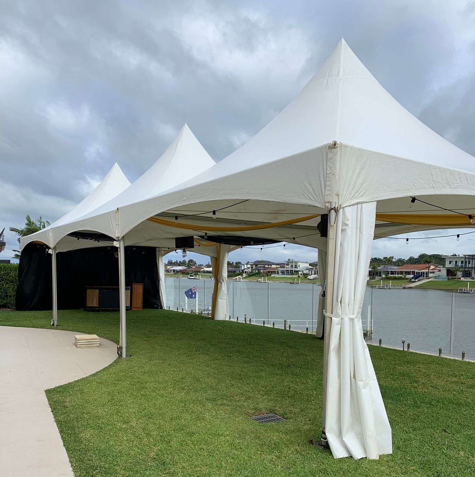 A White Tent Is Sitting In The Grass Near A Body Of Water — Red Shed Hire In Wauchope, NSW