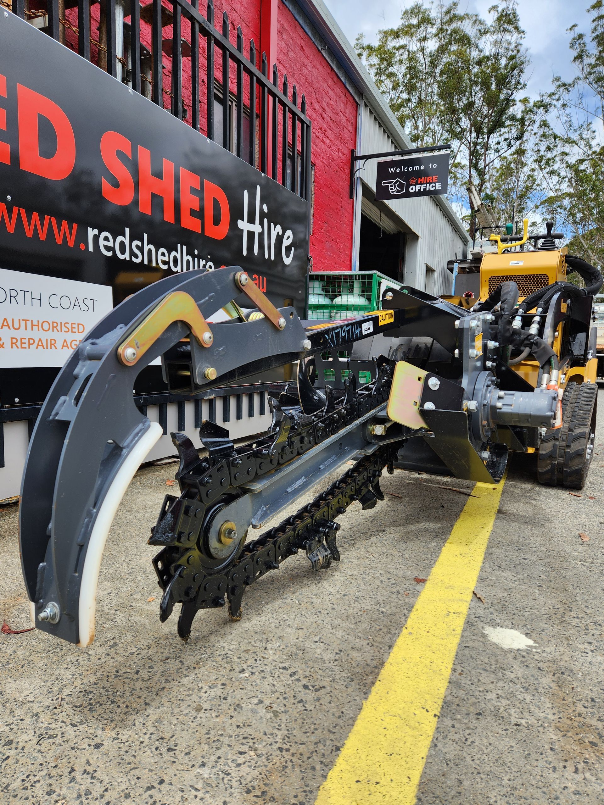 A Machine Is Parked In Front Of A Red Shed Hire Sign — Red Shed Hire In Wauchope, NSW