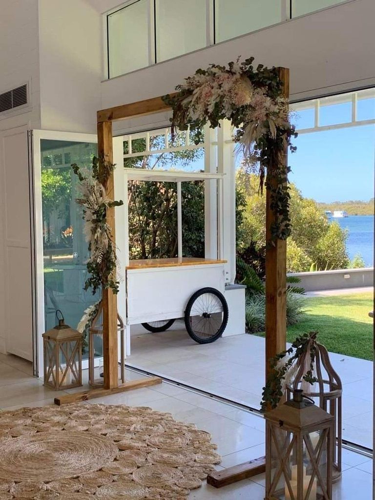 A Wooden Arch With Flowers And Lanterns In A Room — Red Shed Hire In Wauchope, NSW