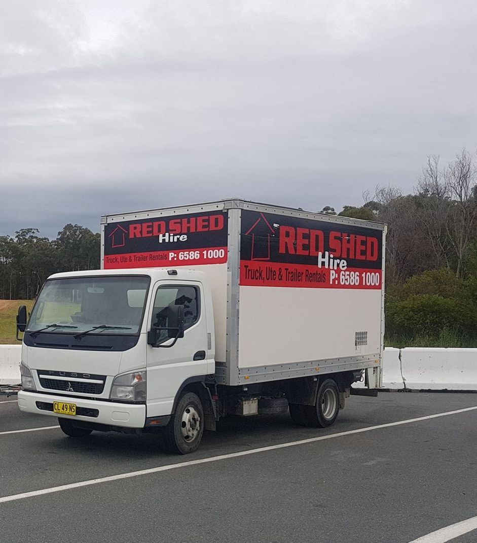 A Red Shed Truck Is Parked On The Side Of The Road — Red Shed Hire In Wauchope, NSW