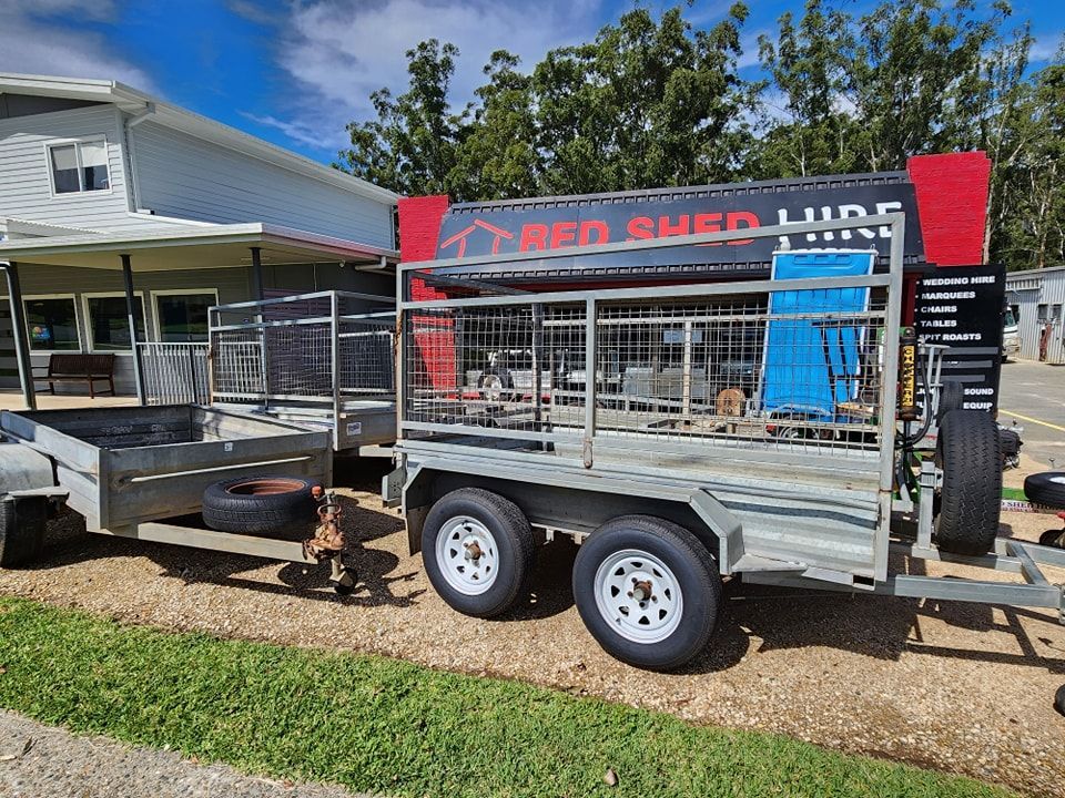 Two trailers parked in front of a building. One has a cage and signage for 