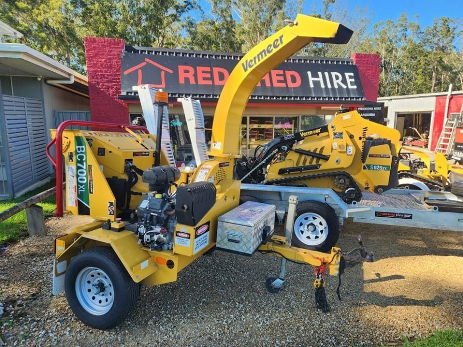 A Yellow Machine Is Parked In Front Of A Red Hire Sign — Red Shed Hire In Wauchope, NSW