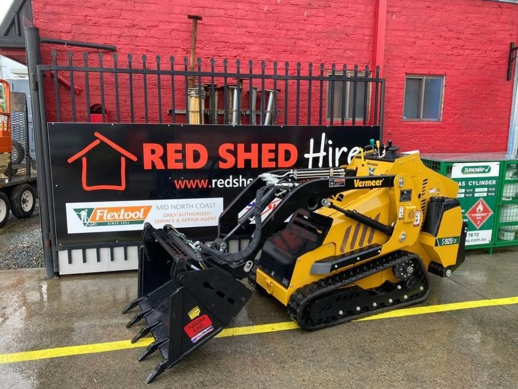 A Yellow Tractor Is Parked In Front Of A Red Shed Hire Sign — Red Shed Hire In Wauchope, NSW