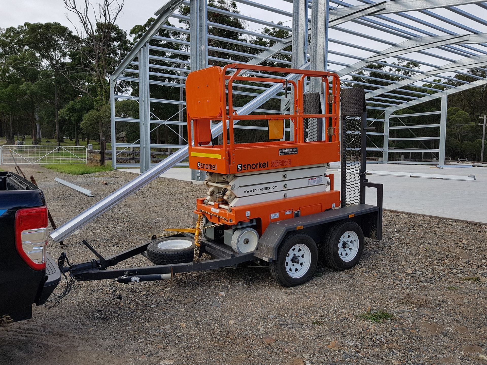 An Orange Scissor Lift Is On A Trailer Attached To A Truck — Red Shed Hire In Wauchope, NSW