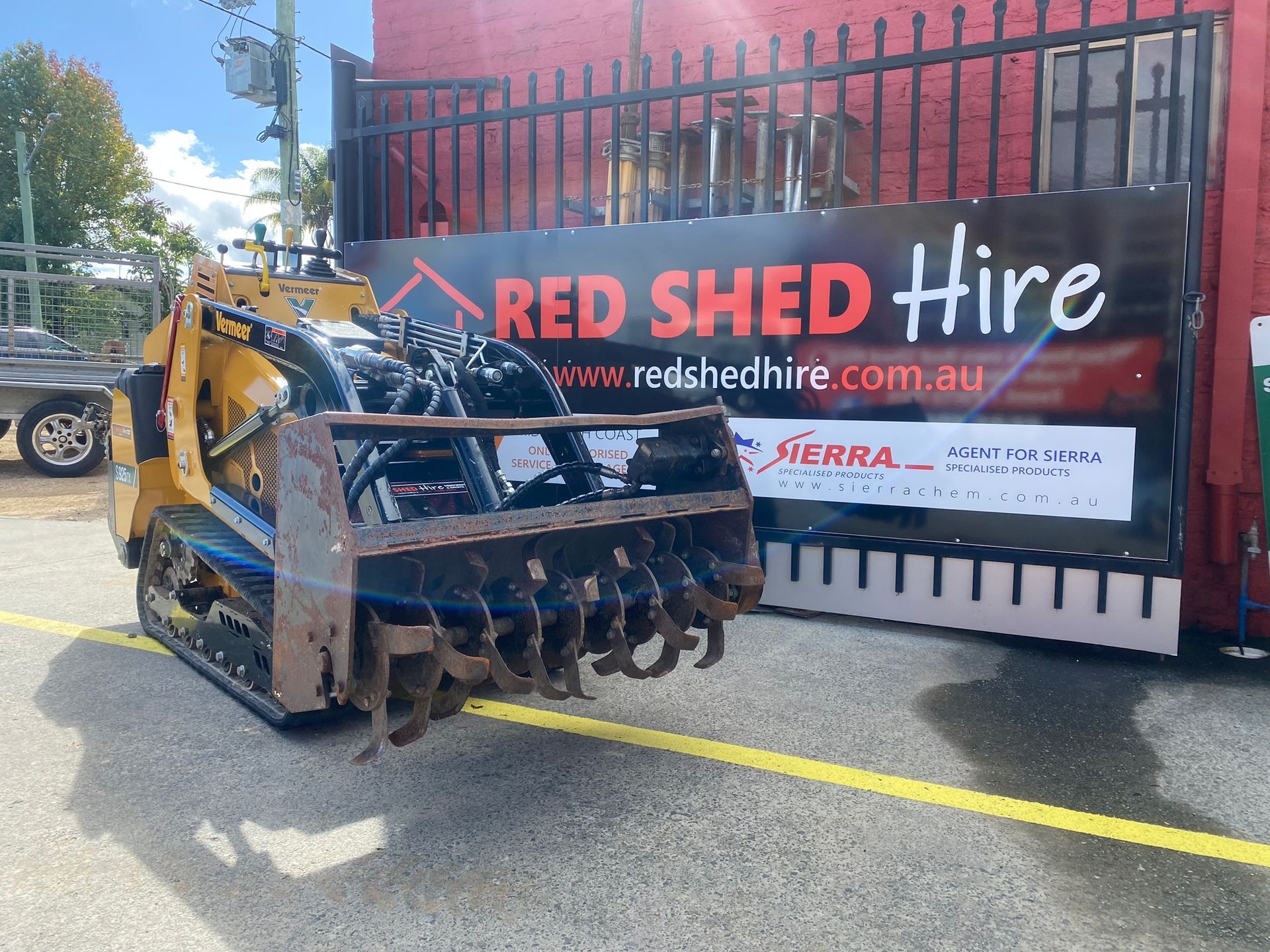 A Tractor Is Parked In Front Of A Red Shed Hire Sign — Red Shed Hire In Wauchope, NSW