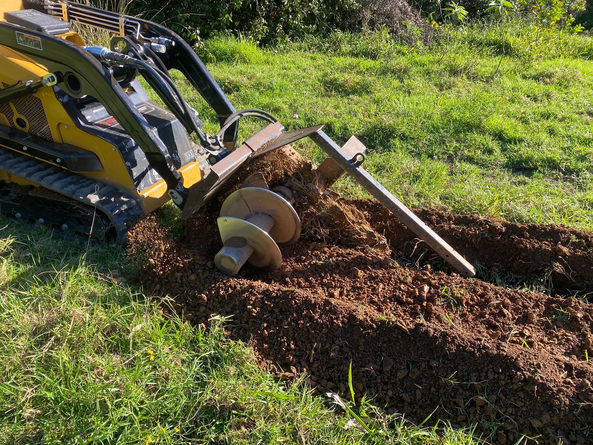 A Yellow Tractor Is Digging A Hole In The Ground — Red Shed Hire In Wauchope, NSW