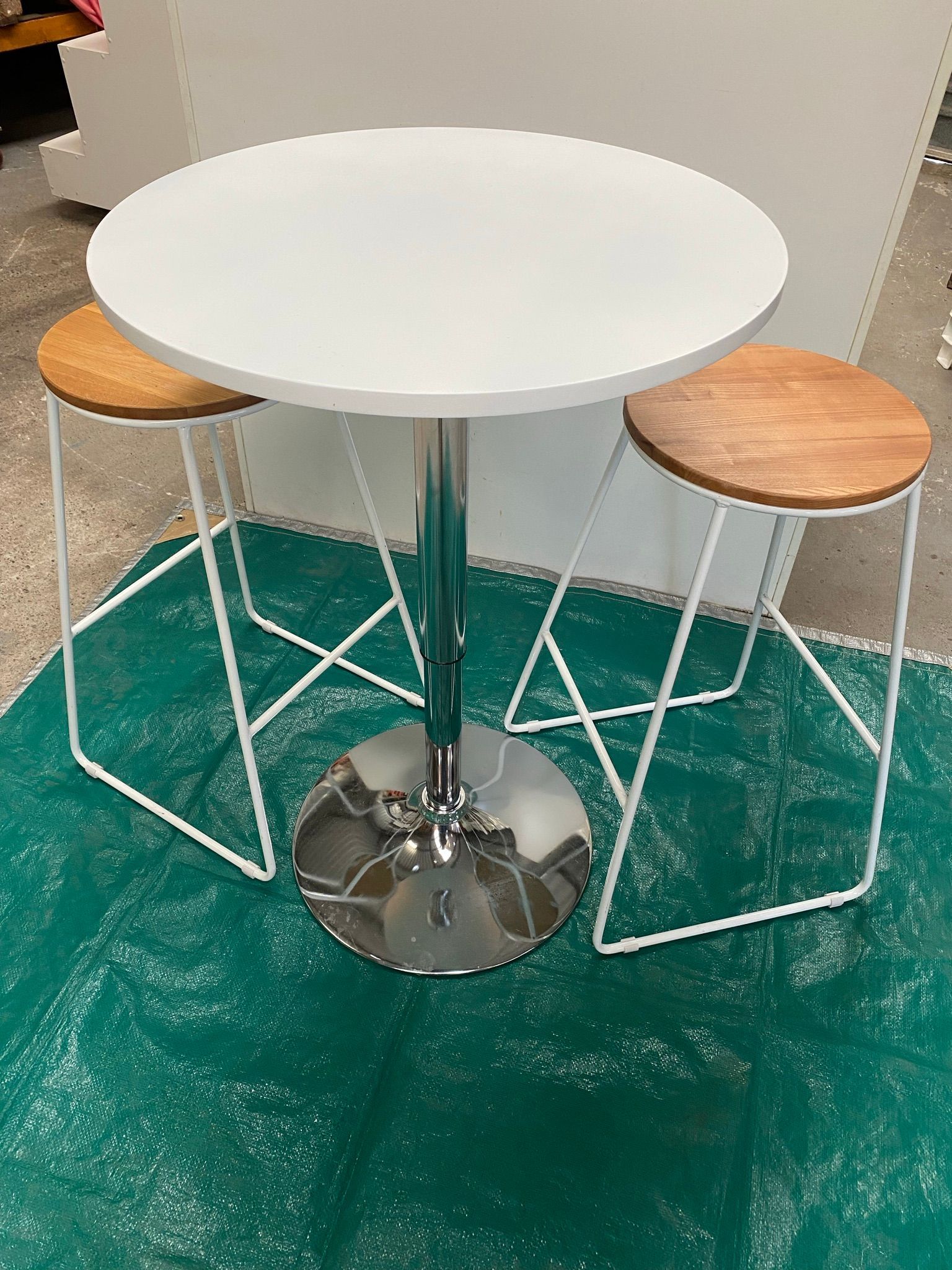 A White Table With Two Wooden Stools On A Green Rug — Red Shed Hire In Wauchope, NSW