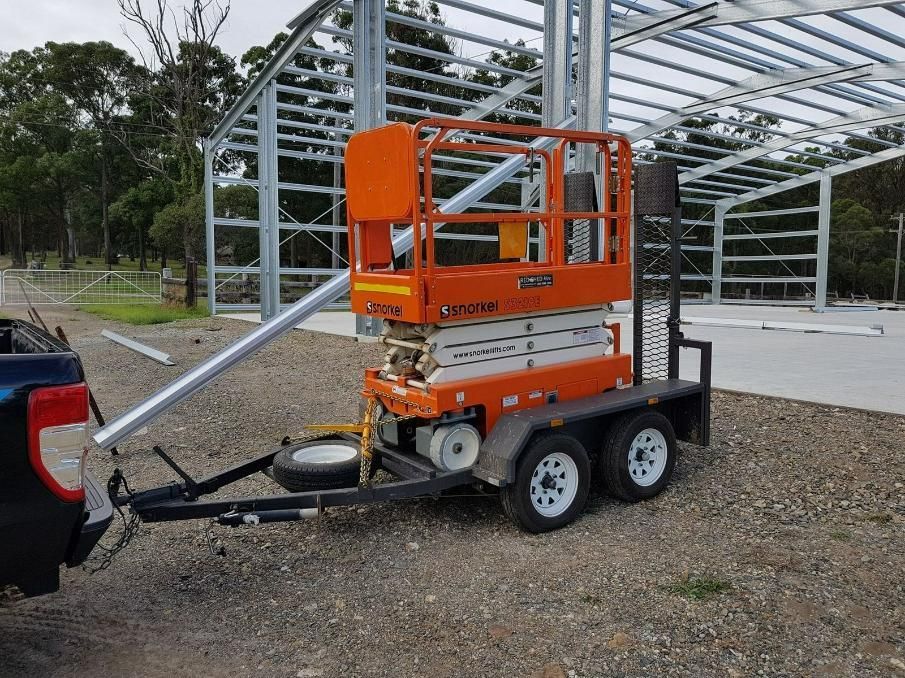 An Orange Scissor Lift Is On A Trailer Attached To A Truck — Red Shed Hire In Wauchope, NSW