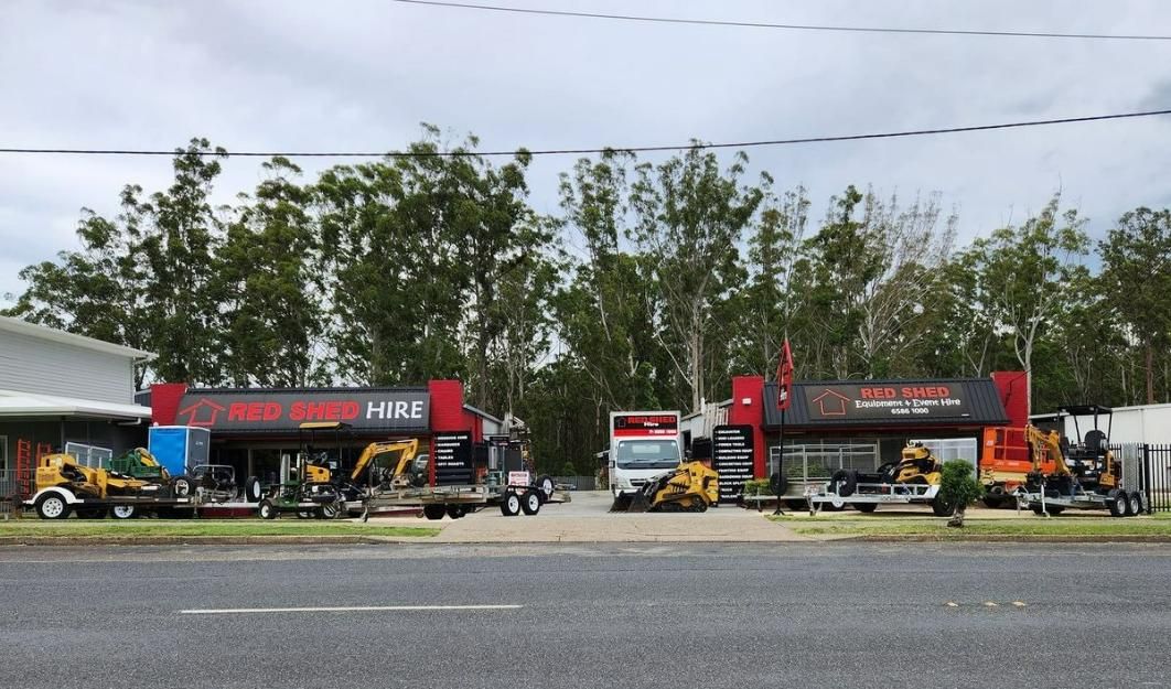 A Large Building With A Lot Of Trucks Parked In Front Of It — Red Shed Hire In Wauchope, NSW