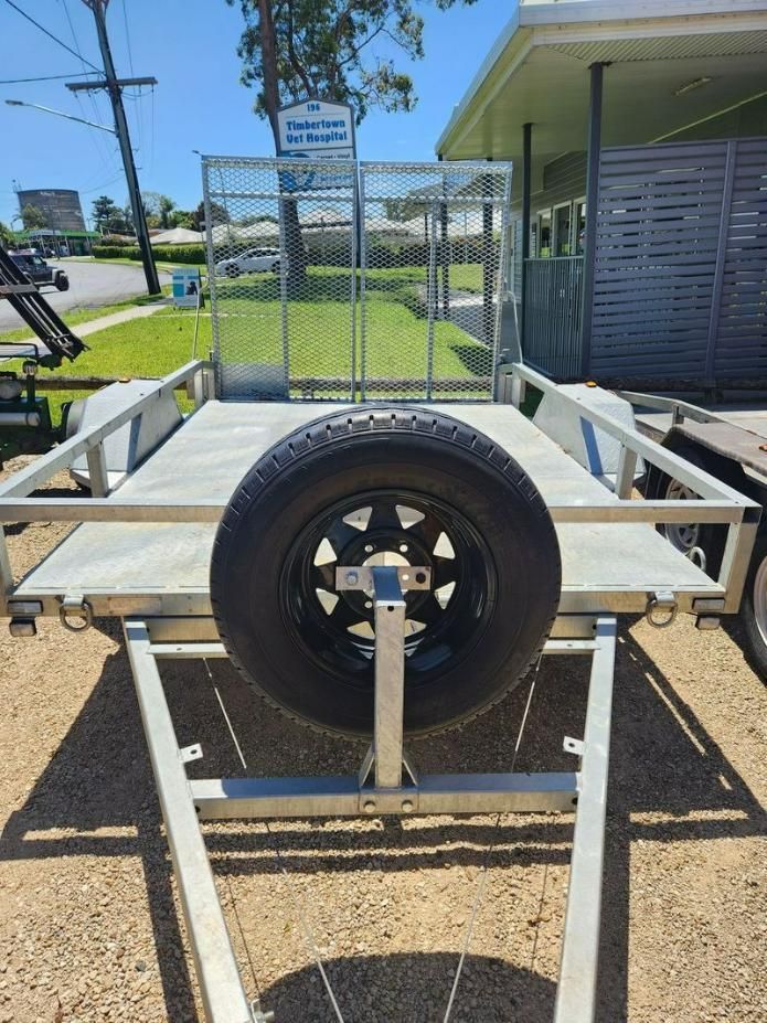 A Trailer With A Spare Tire Attached To It Is Parked On The Side Of The Road — Red Shed Hire In Wauchope, NSW