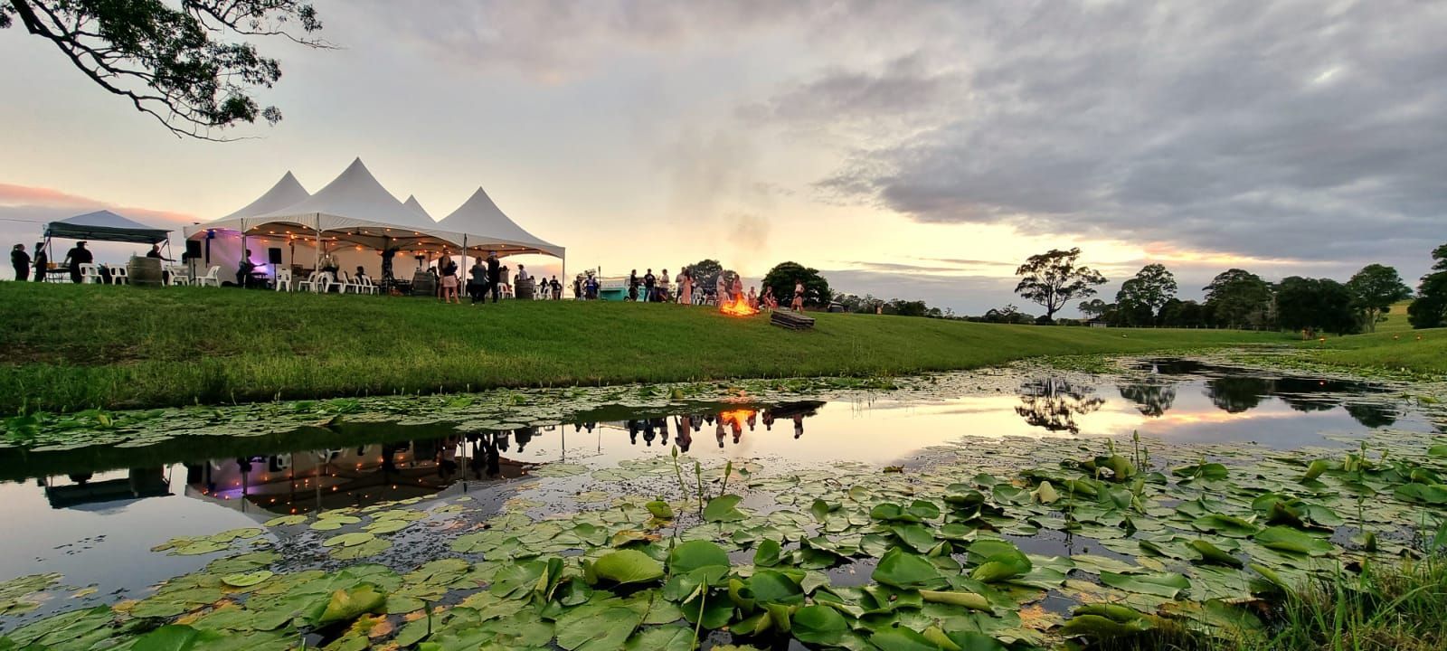A Group Of People Are Standing In A Field Next To A Pond — Red Shed Hire In Wauchope, NSW