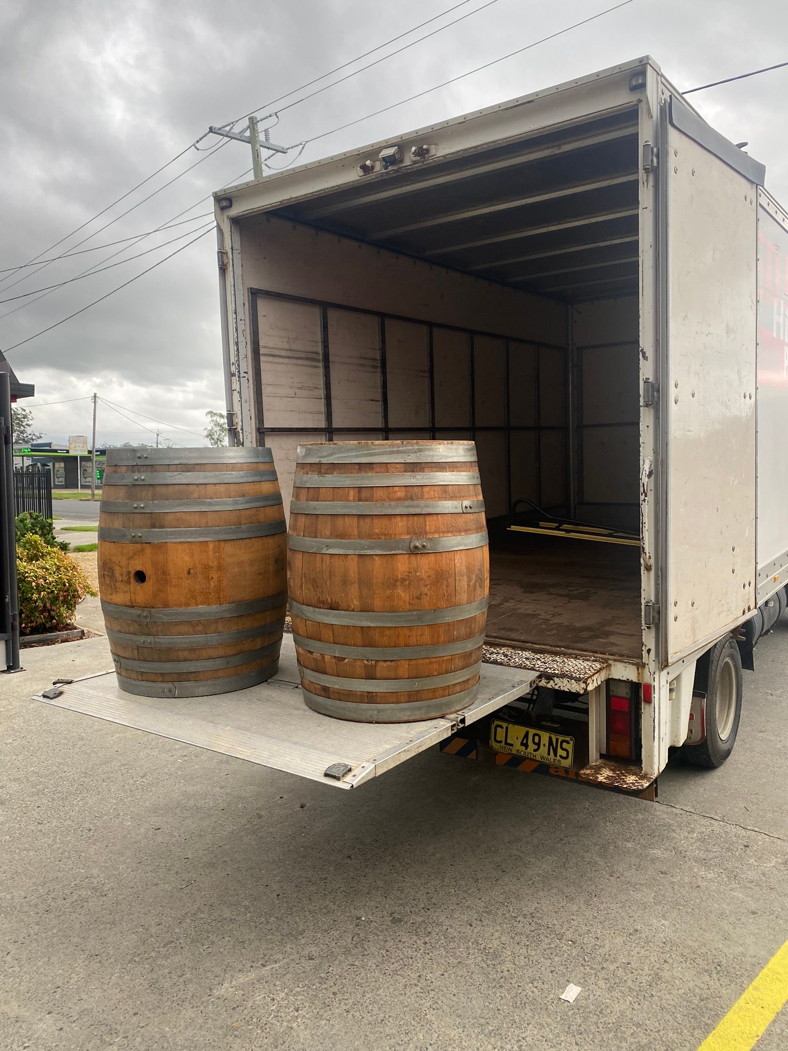 Two Wooden Barrels Are Sitting On The Back Of A Truck — Red Shed Hire In Wauchope, NSW