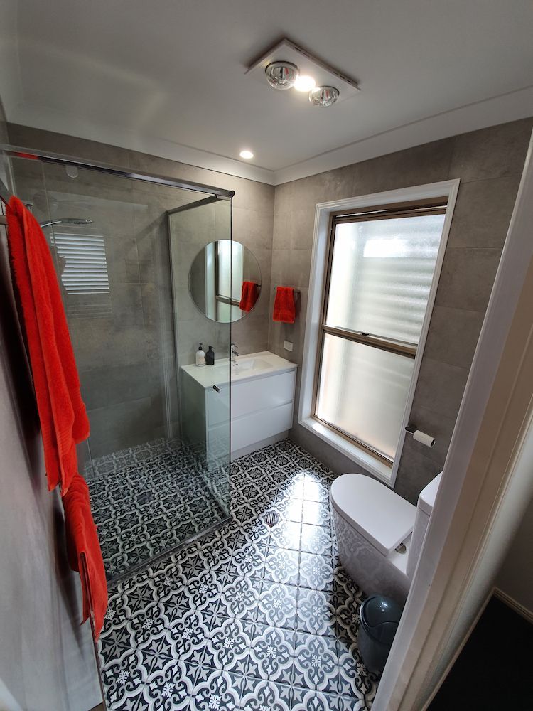A Bathroom With a Walk in Shower, Toilet, Sink and Mirror — Coastwide Plumbing Solutions in Sippy Downs, QLD