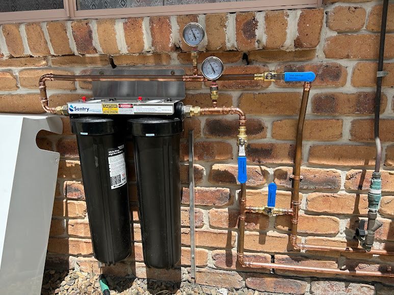 A Water Filter is Attached to a Brick Wall — Coastwide Plumbing Solutions in Mountain Creek, QLD
